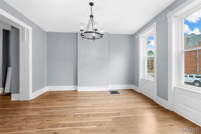 2148 Oregon Ave, Saint Louis, MO 63104 - unfurnished dining area with a chandelier, light wood-style flooring, and baseboards
