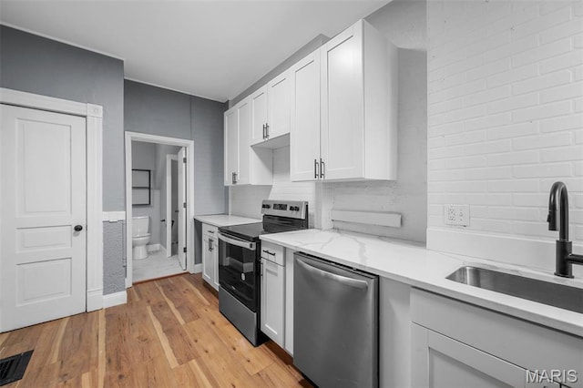 2148 Oregon Ave, Saint Louis, MO 63104 - kitchen with stainless steel appliances, a sink, light wood-type flooring, white cabinetry, and decorative backsplash