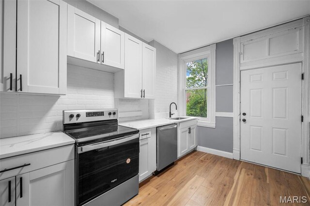 2148 Oregon Ave, Saint Louis, MO 63104 - kitchen featuring appliances with stainless steel finishes, a sink, light wood-style flooring, backsplash, and white cabinetry