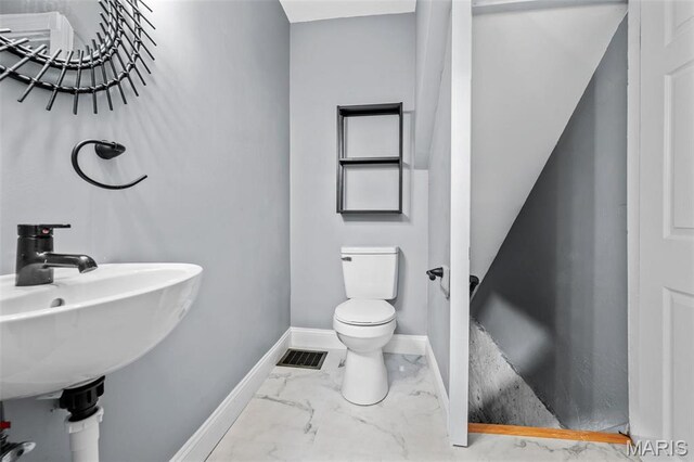 2148 Oregon Ave, Saint Louis, MO 63104 - bathroom with toilet, baseboards, marble look tile flooring, and a sink