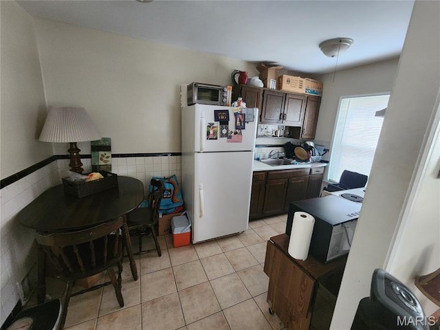 3409 Saint Gregory Ln, Saint Ann, MO 63074 - kitchen with freestanding refrigerator, tile walls, light tile patterned floors, dark brown cabinetry, and a sink