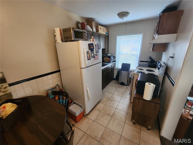 3409 Saint Gregory Ln, Saint Ann, MO 63074 - kitchen with freestanding refrigerator, electric stove, light tile patterned floors, tile walls, and a wainscoted wall