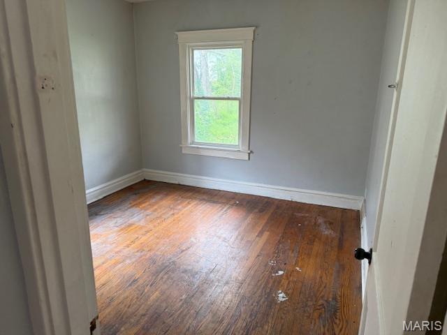 unfurnished room featuring hardwood / wood-style floors and baseboards