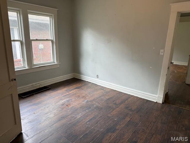 unfurnished room with dark wood-type flooring and baseboards