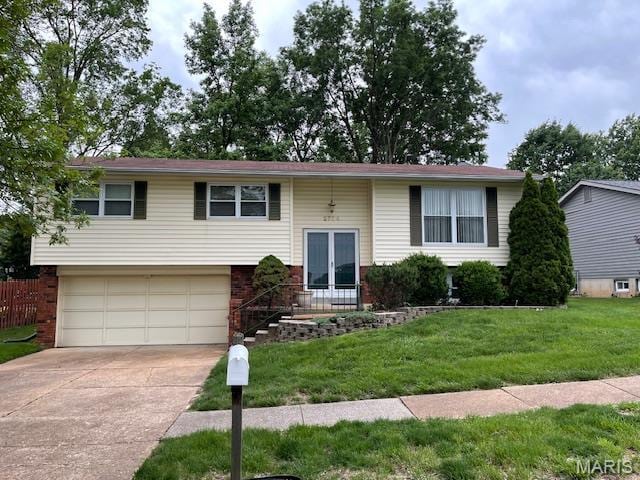 raised ranch with brick siding, a garage, driveway, and a front lawn
