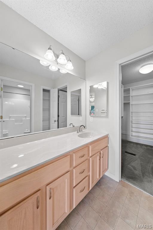1149 Silo Bnd Unit 341A, Wentzville, MO 63385 - full bath with vanity, a walk in closet, a textured ceiling, and tile patterned flooring