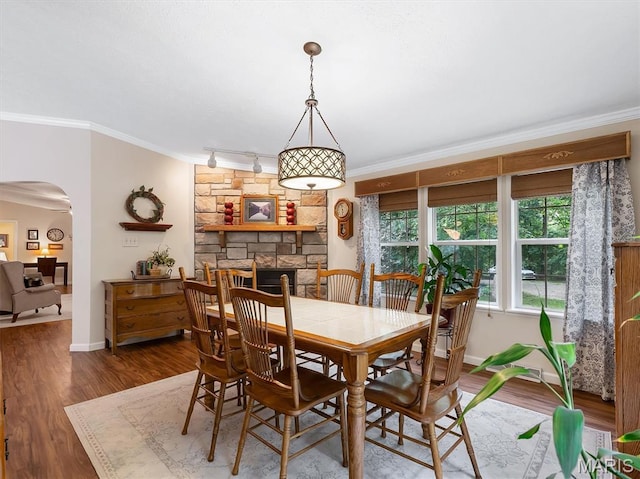 3870 Wilkinson Rd, De Soto, MO 63020 - dining space featuring arched walkways, ornamental molding, rail lighting, wood finished floors, and a stone fireplace