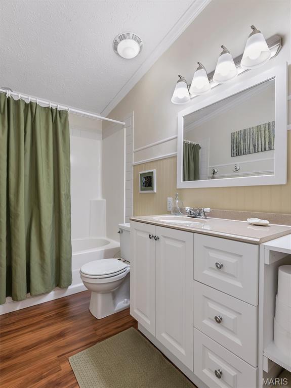 3870 Wilkinson Rd, De Soto, MO 63020 - bathroom featuring vanity, wood finished floors, shower / bath combination with curtain, ornamental molding, and a textured ceiling