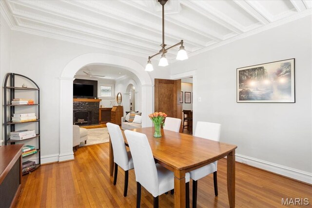 7440 Kingsbury Blvd, Saint Louis, MO 63130 - dining space with a fireplace, ornamental molding, arched walkways, wood finished floors, and baseboards