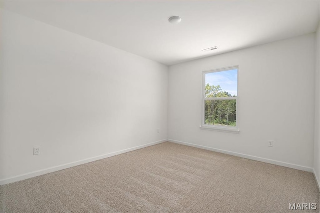 spare room featuring carpet and baseboards