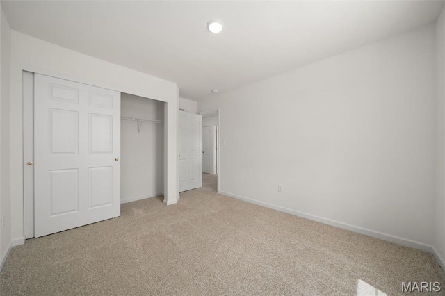 unfurnished bedroom with light carpet, a closet, and baseboards