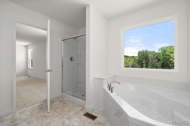bathroom featuring a stall shower, a bath, and baseboards