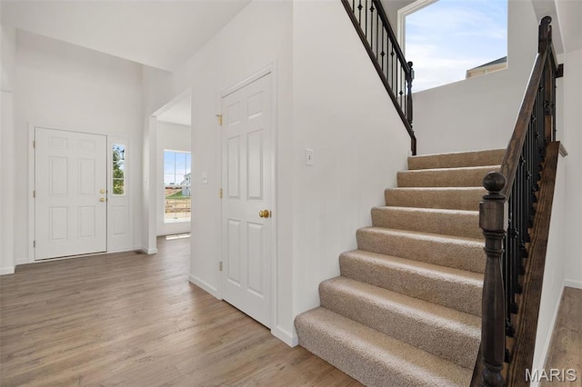 entryway with wood finished floors, stairs, and baseboards