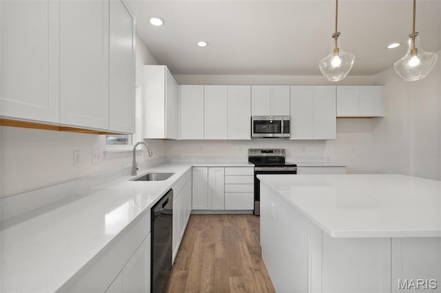 kitchen featuring stainless steel appliances, a sink, light wood finished floors, white cabinetry, and recessed lighting
