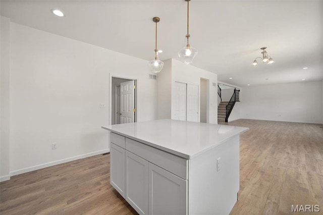 kitchen featuring light wood-style floors, a center island, pendant lighting, light countertops, and open floor plan