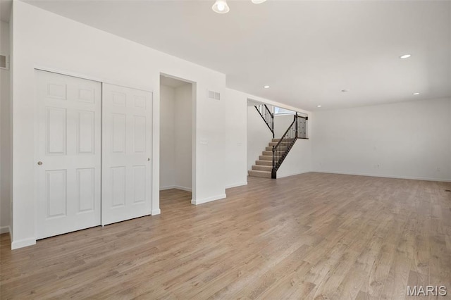 unfurnished living room featuring stairway, light wood-type flooring, baseboards, and recessed lighting