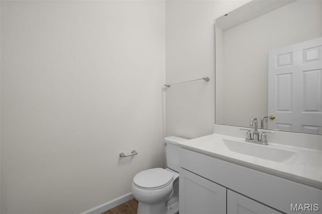 bathroom with wood finished floors, toilet, vanity, and baseboards