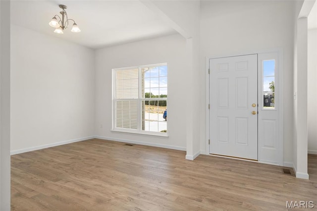 entryway featuring a chandelier, baseboards, and light wood-style floors