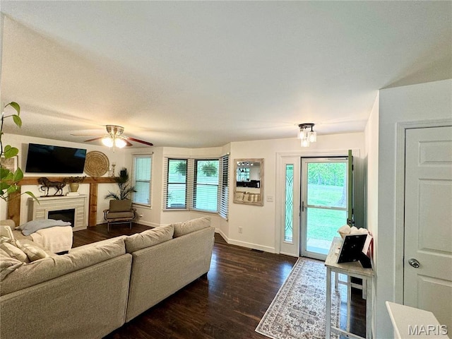 living room with baseboards, dark wood-style flooring, a fireplace, and ceiling fan