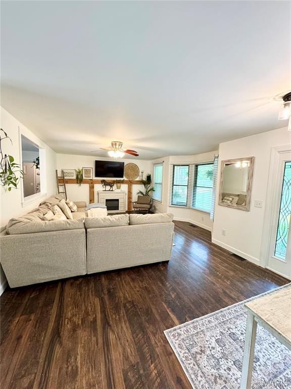 living room featuring ceiling fan, wood finished floors, baseboards, and a fireplace