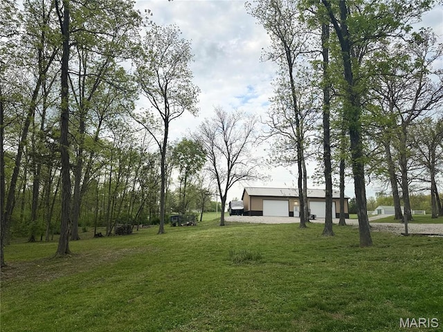 view of grassy yard featuring an outbuilding, driveway, and a garage