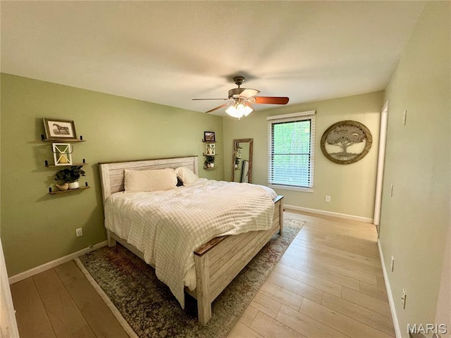 bedroom with light wood-style flooring, baseboards, and a ceiling fan