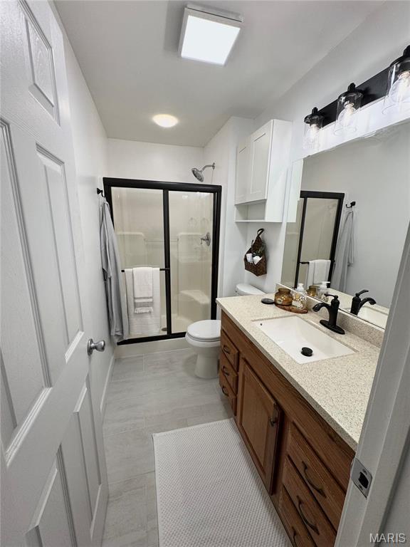 full bath with a stall shower, vanity, toilet, and tile patterned floors