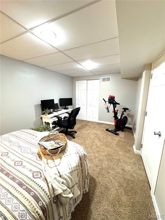 carpeted bedroom with a paneled ceiling and baseboards