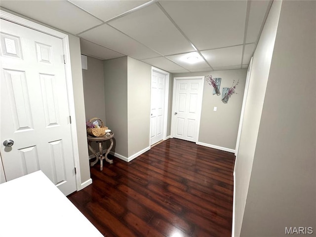 basement featuring wood finished floors, baseboards, and a paneled ceiling