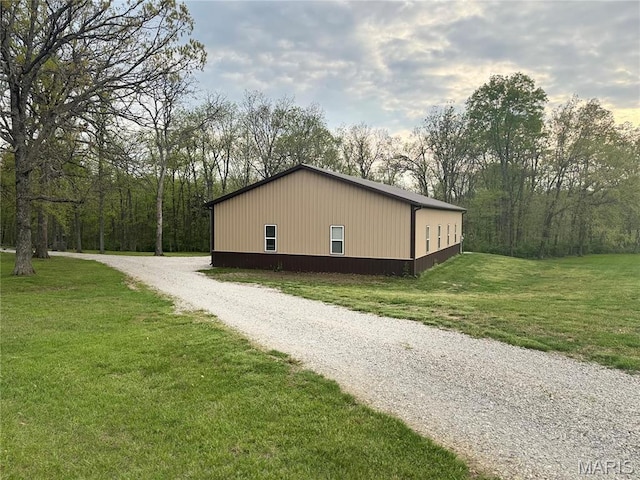 view of side of property featuring driveway and a lawn