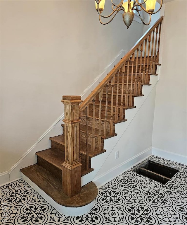 stairway featuring a chandelier, baseboards, and tile patterned flooring