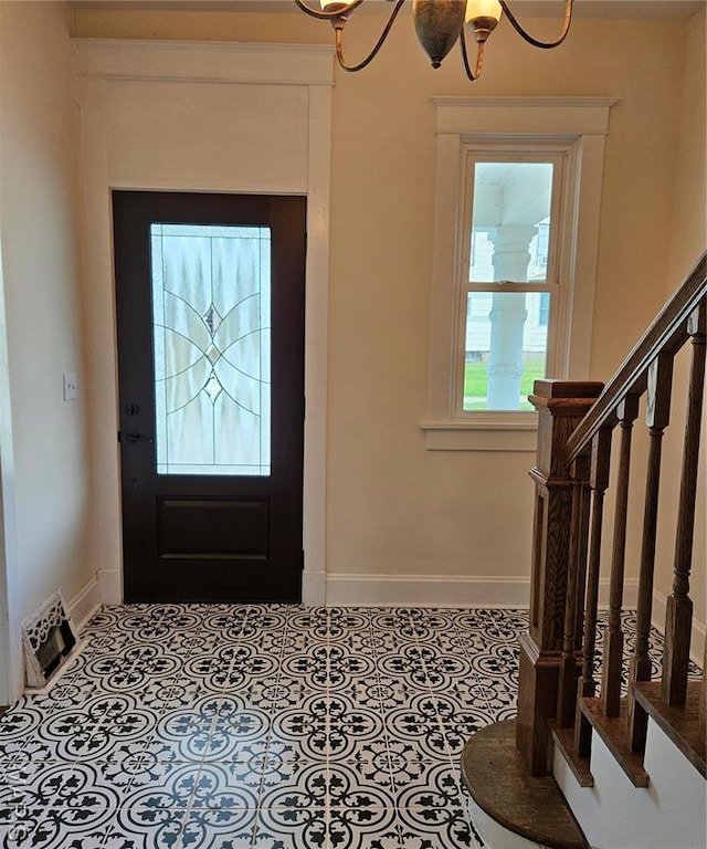 foyer with baseboards, a chandelier, and stairs