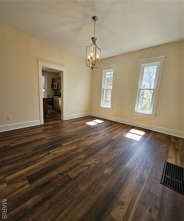 unfurnished dining area with a chandelier, dark wood-type flooring, and baseboards