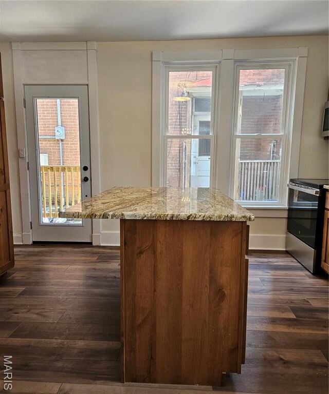 kitchen with stainless steel range with electric cooktop, dark wood-type flooring, light stone counters, baseboards, and a center island