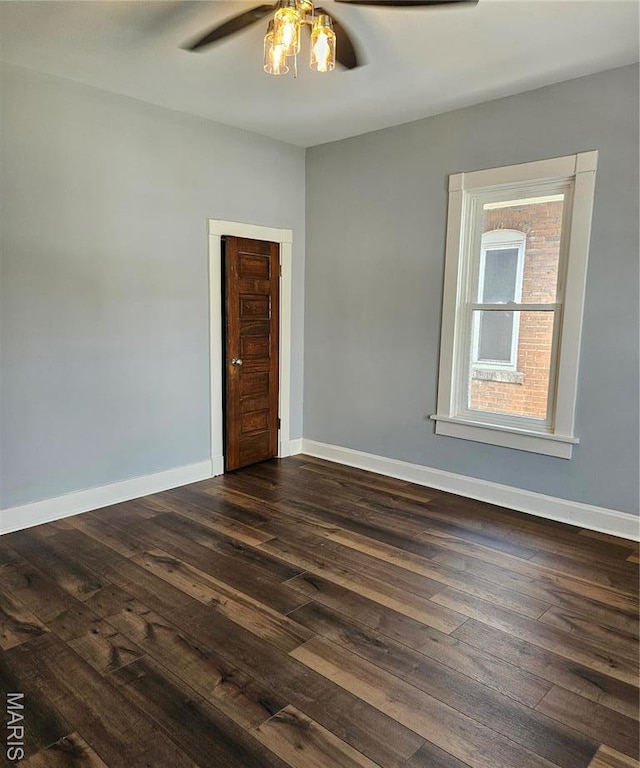 unfurnished room with a ceiling fan, dark wood finished floors, and baseboards