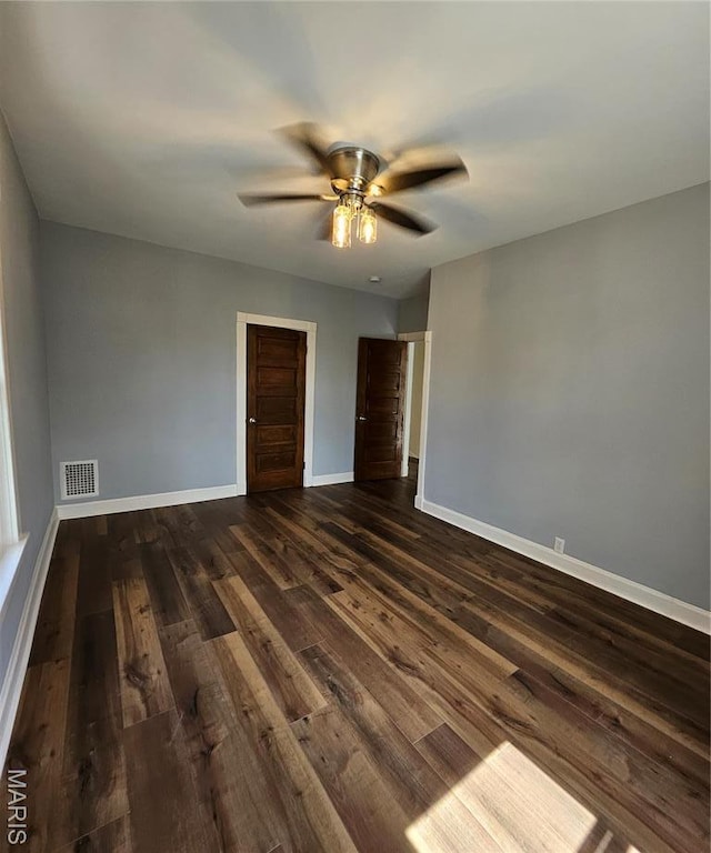 unfurnished room featuring dark wood finished floors, baseboards, and a ceiling fan