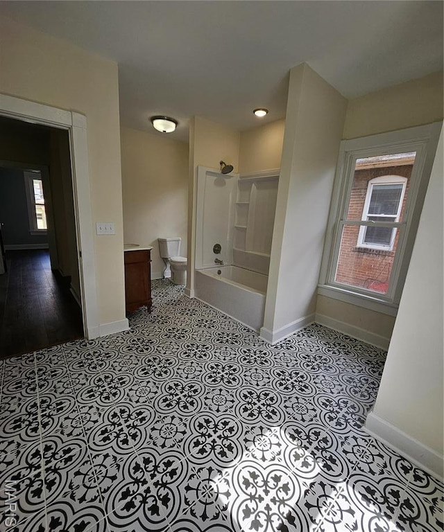 bathroom featuring baseboards, shower / washtub combination, toilet, and vanity