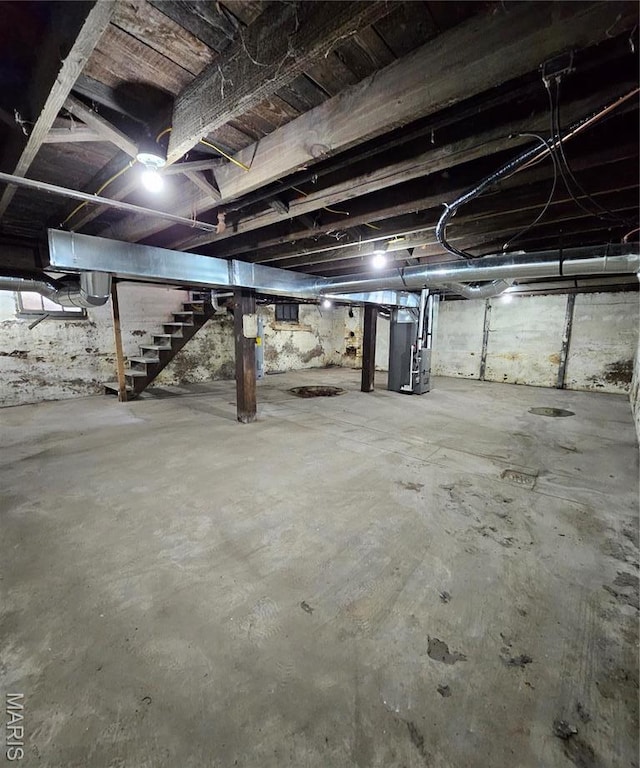 unfinished basement featuring stairway and heating unit