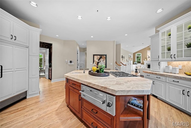 kitchen featuring a warming drawer, plenty of natural light, a sink, light wood finished floors, and recessed lighting