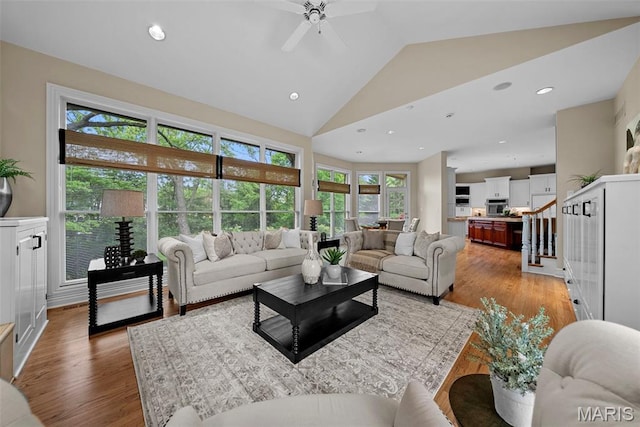 living area with healthy amount of natural light, a ceiling fan, light wood-style flooring, recessed lighting, and high vaulted ceiling