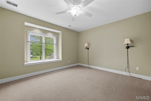 carpeted spare room featuring baseboards and ceiling fan