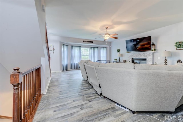 904 Indian Rock Ct, Wentzville, MO 63385 - living room featuring light wood-style flooring, ceiling fan, a glass covered fireplace, and baseboards