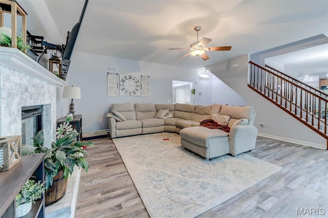 904 Indian Rock Ct, Wentzville, MO 63385 - living room featuring ceiling fan, light wood finished floors, stairs, and a fireplace with raised hearth