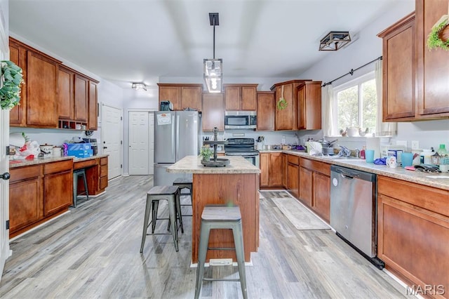 904 Indian Rock Ct, Wentzville, MO 63385 - kitchen with stainless steel appliances, brown cabinets, a kitchen breakfast bar, and light wood finished floors
