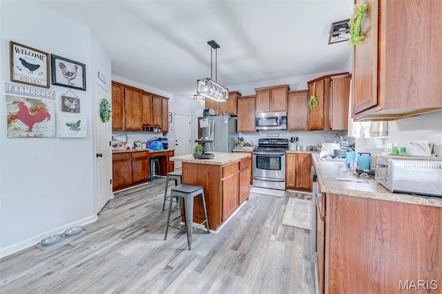 904 Indian Rock Ct, Wentzville, MO 63385 - kitchen with appliances with stainless steel finishes, brown cabinetry, a kitchen island, and light wood-style flooring