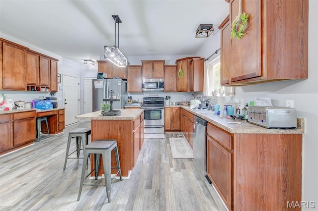 904 Indian Rock Ct, Wentzville, MO 63385 - kitchen featuring stainless steel appliances, a breakfast bar, brown cabinetry, and light wood-type flooring