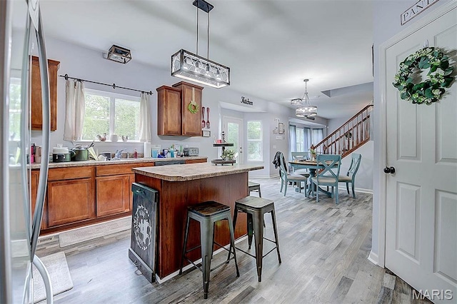 904 Indian Rock Ct, Wentzville, MO 63385 - kitchen with brown cabinets, stainless steel refrigerator, light wood finished floors, and a kitchen island