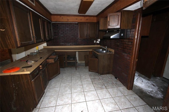 9434 Joan Ct, Bonne Terre, MO 63628 - kitchen with a sink, under cabinet range hood, light tile patterned floors, brick wall, and dark brown cabinetry