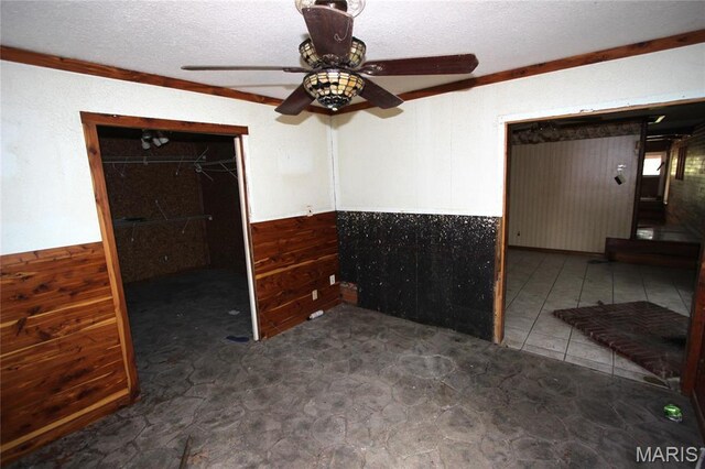 9434 Joan Ct, Bonne Terre, MO 63628 - spare room with wainscoting, wood walls, a ceiling fan, and a textured ceiling