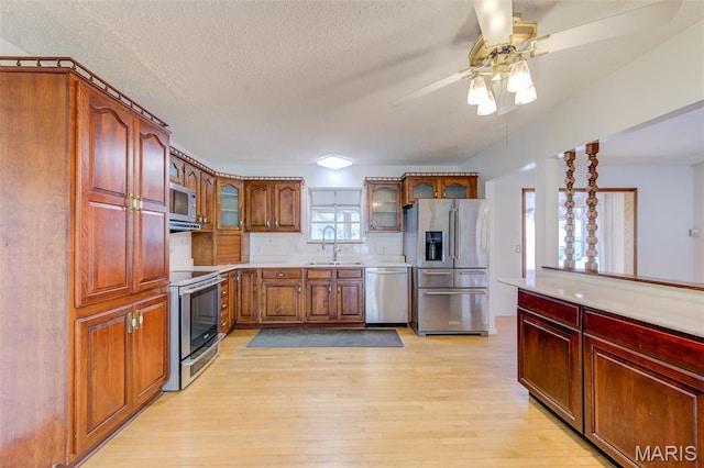 24 Shaw Ct, Cottleville Township, MO 63304 - kitchen featuring appliances with stainless steel finishes, light wood-style floors, glass insert cabinets, light countertops, and a ceiling fan